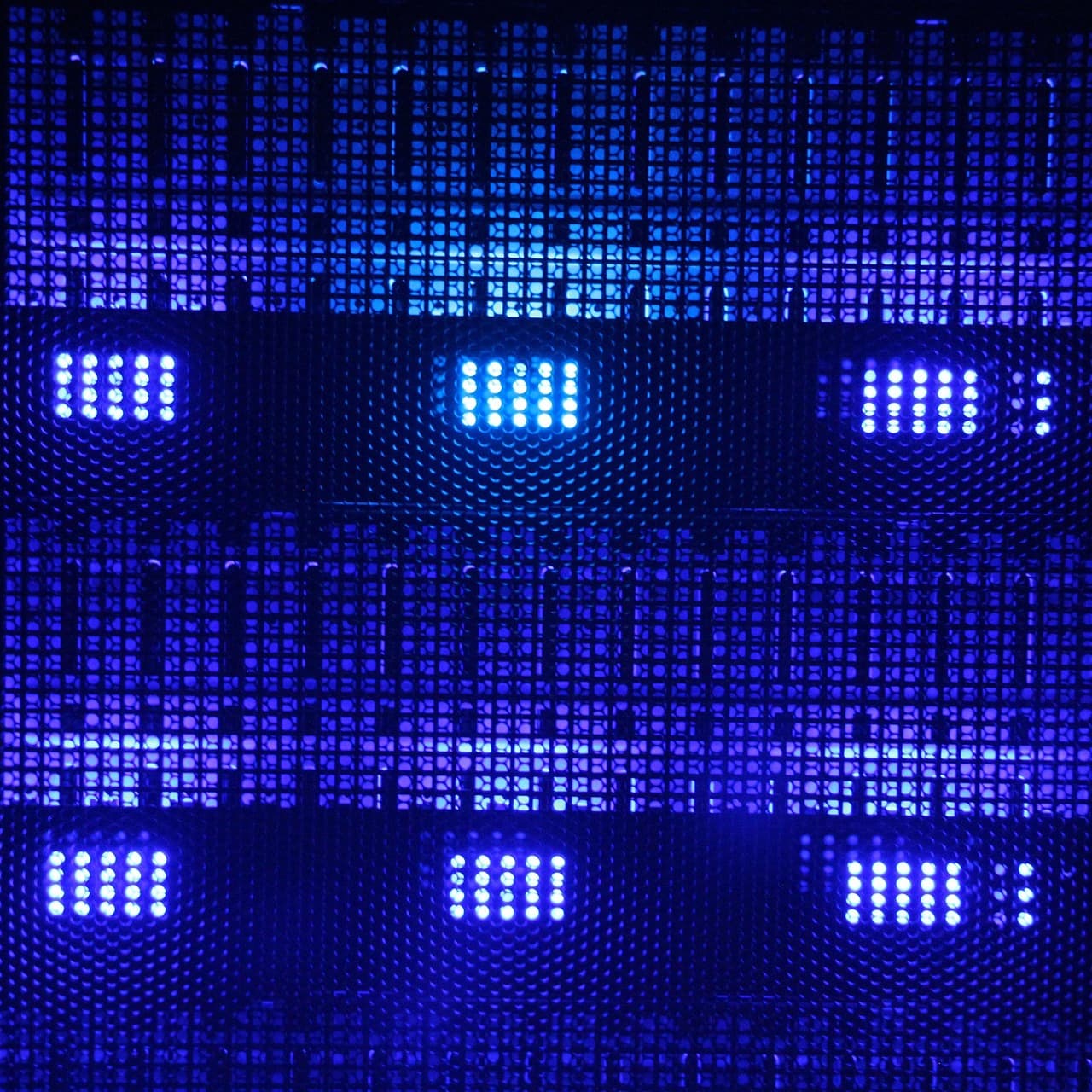 File di spie luminose blu dietro la griglia forata di un armadio server