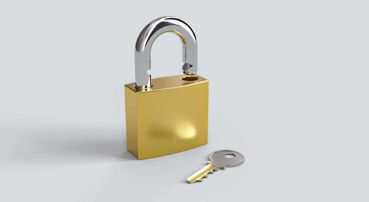 Ein 3D-gerendertes Vorhängeschloss aus Messing steht offen mit ausgeklinktem Bügel, daneben liegt ein kleiner Schlüssel auf der grauen Oberfläche.