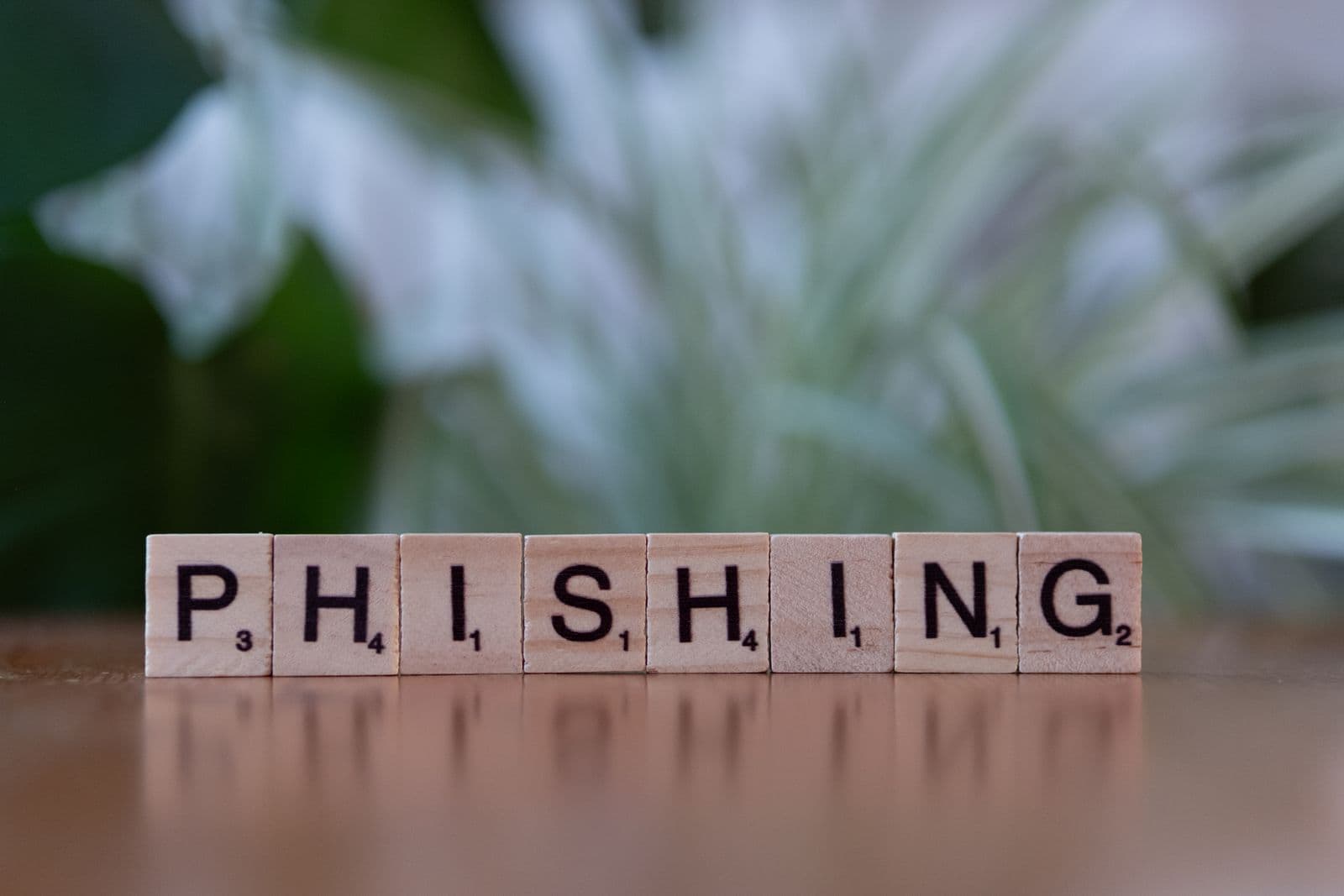 Wooden tiles spelling out the word phishing. Modern phishing kits do not just steal passwords - they capture the session after you pass MFA.